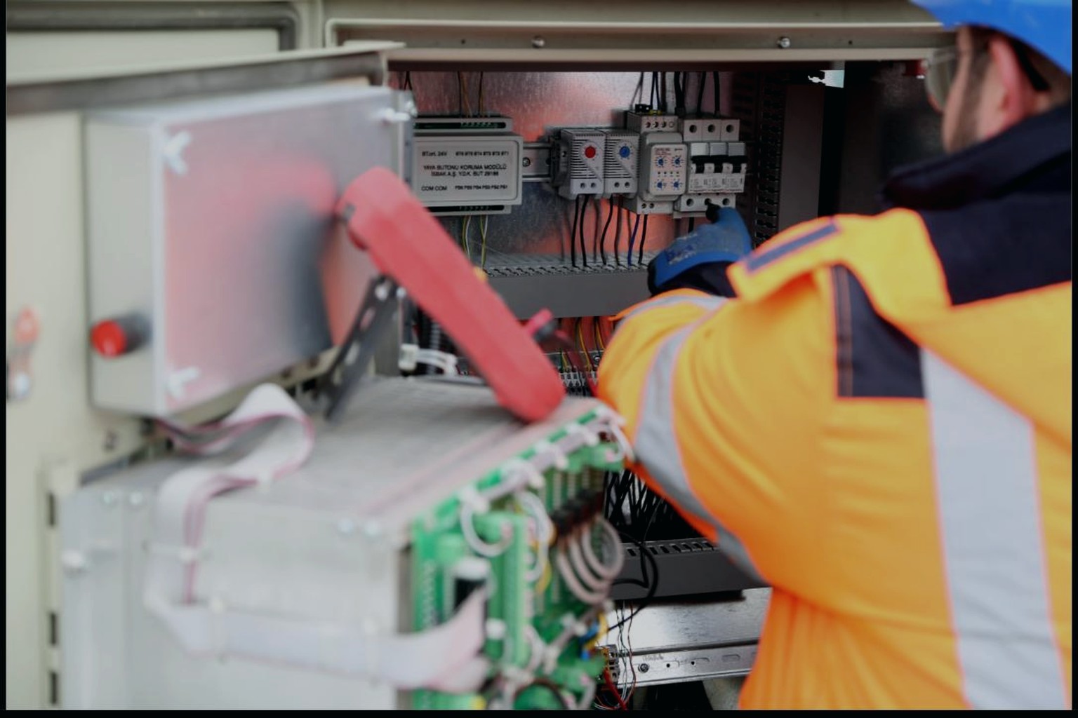 Technician in a high-visibility vest servicing a control panel