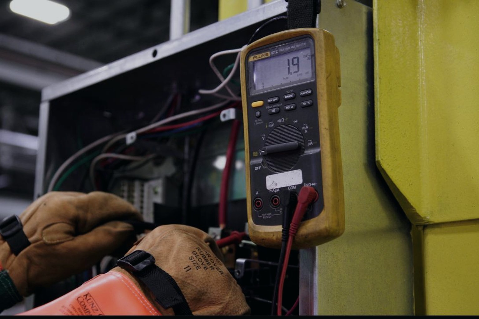Technician checking a control panel with a multimeter