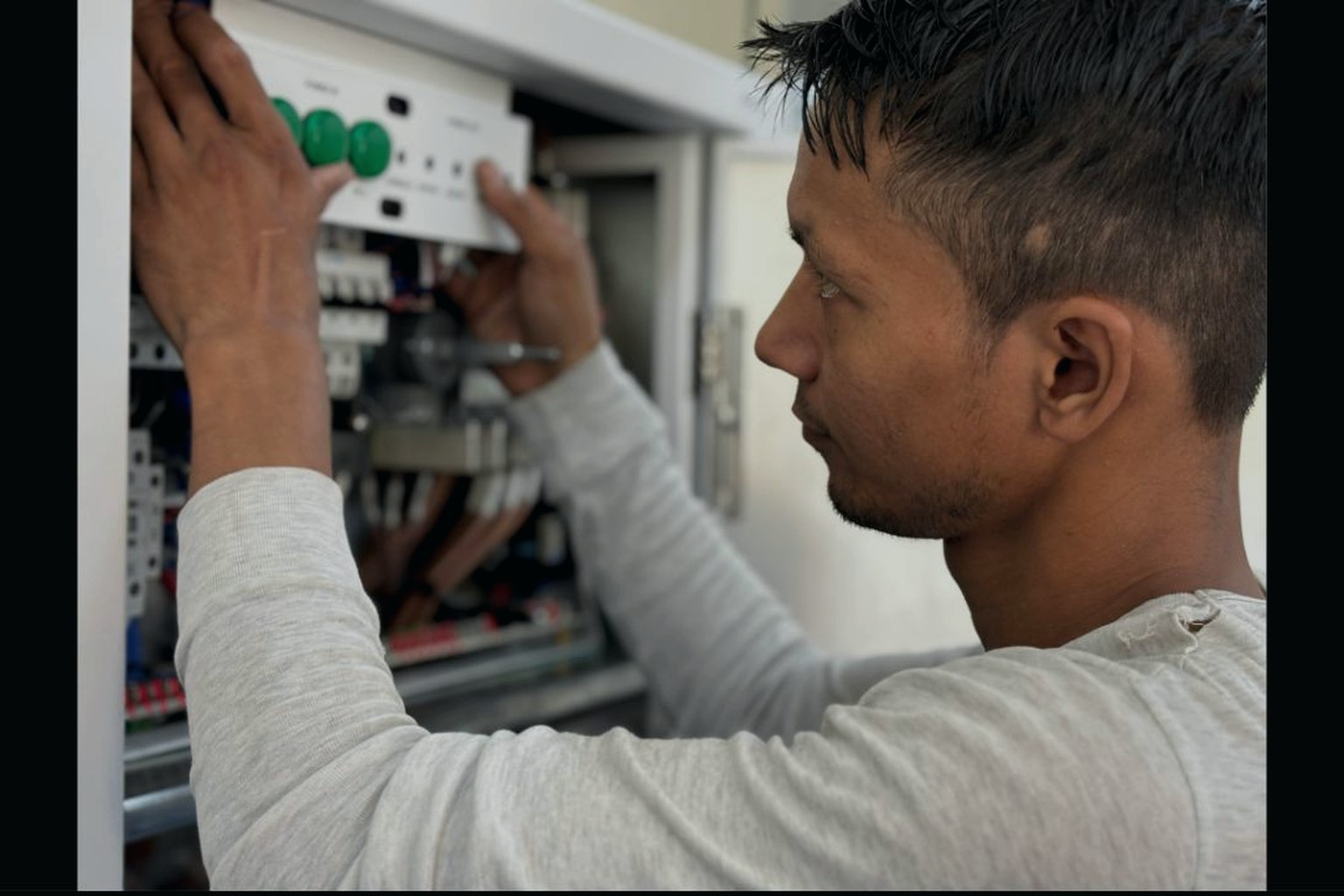 Technician installing equipment in an electrical panel